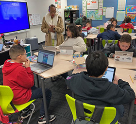 Teacher watching students work on their laptops